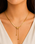 Gold necklace with a butterfly pendant on a model wearing a white top.