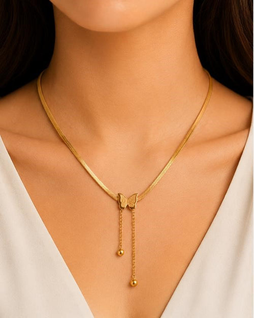 Gold necklace with a butterfly pendant on a model wearing a white top.